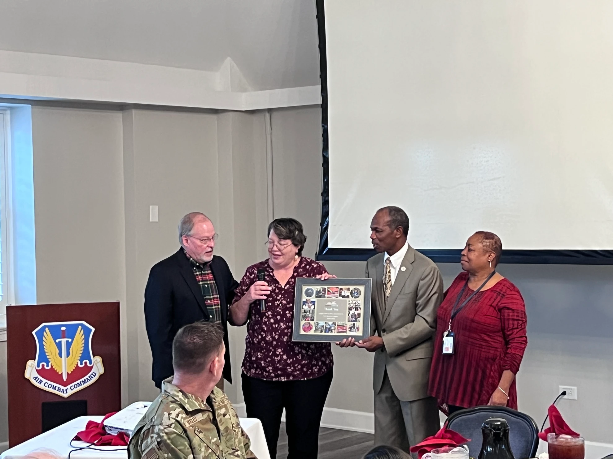 Award ceremony with Air Combat Command emblem visible