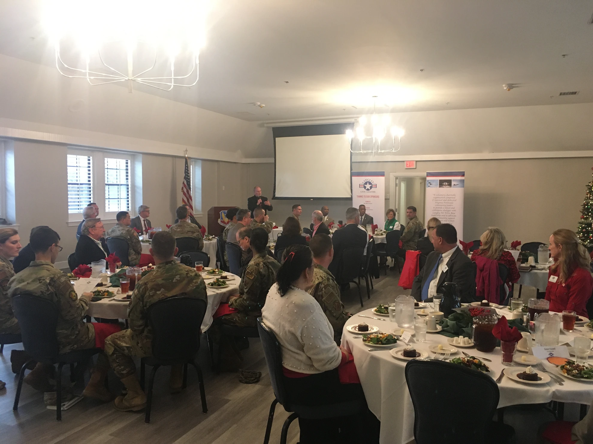 Full room view with speaker at podium and attendees at tables