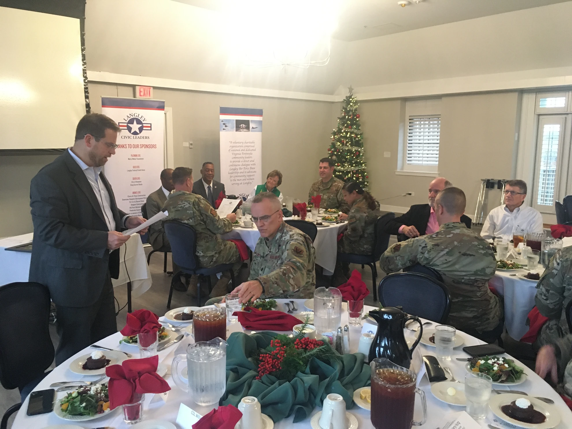 Holiday luncheon scene with speaker and attendees at tables