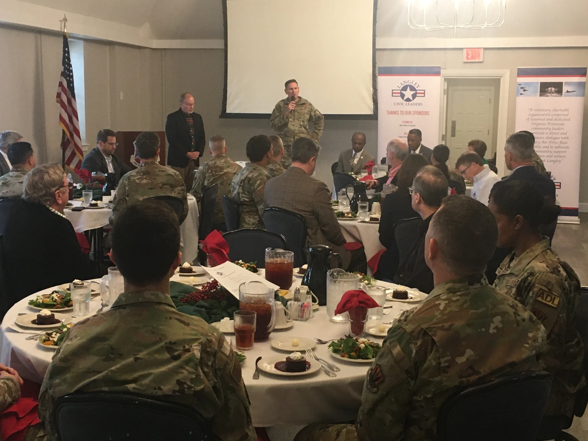 Military officer addressing room with LCLA banners visible