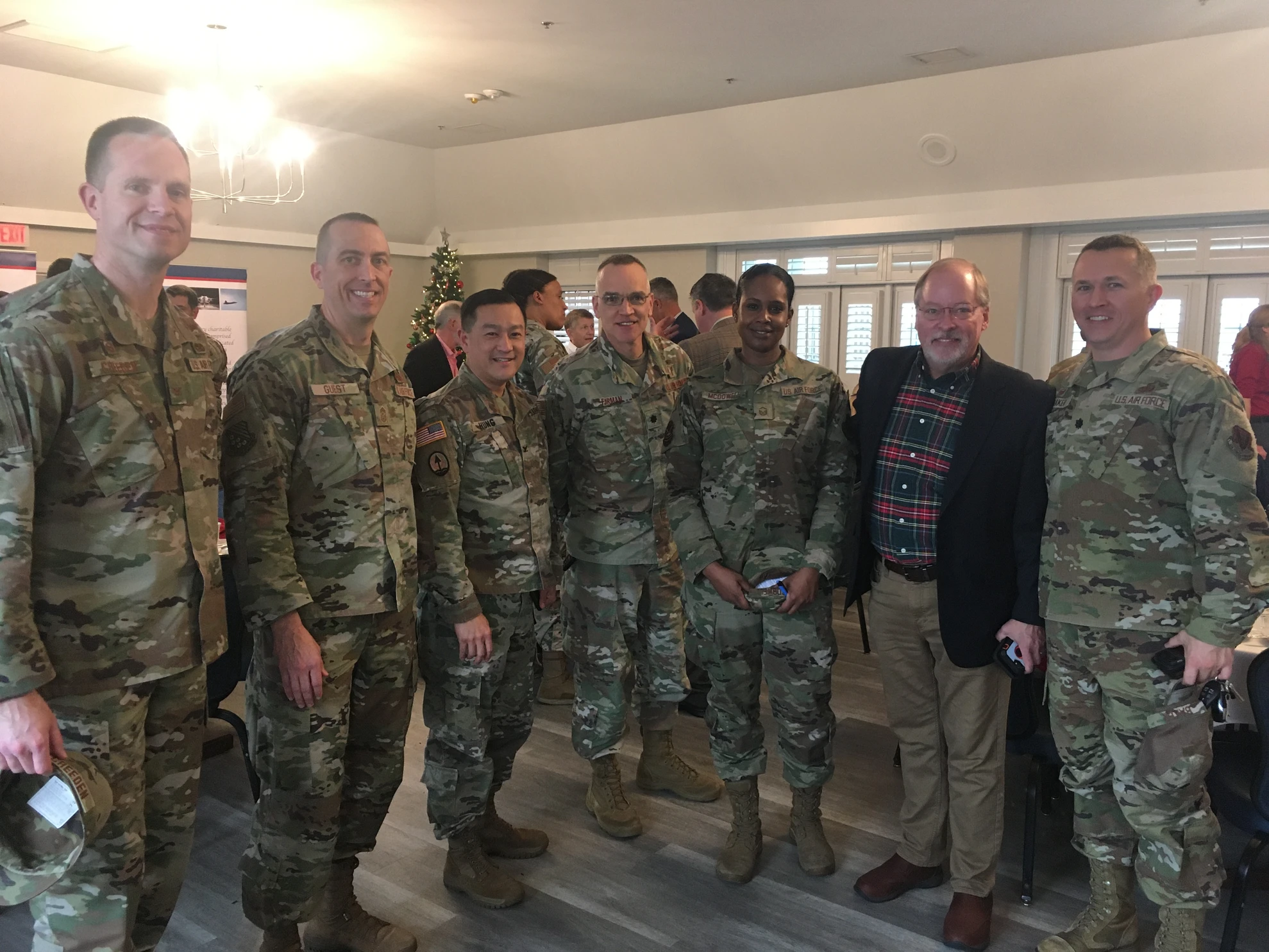 Group of military personnel and civilian in plaid shirt posing together