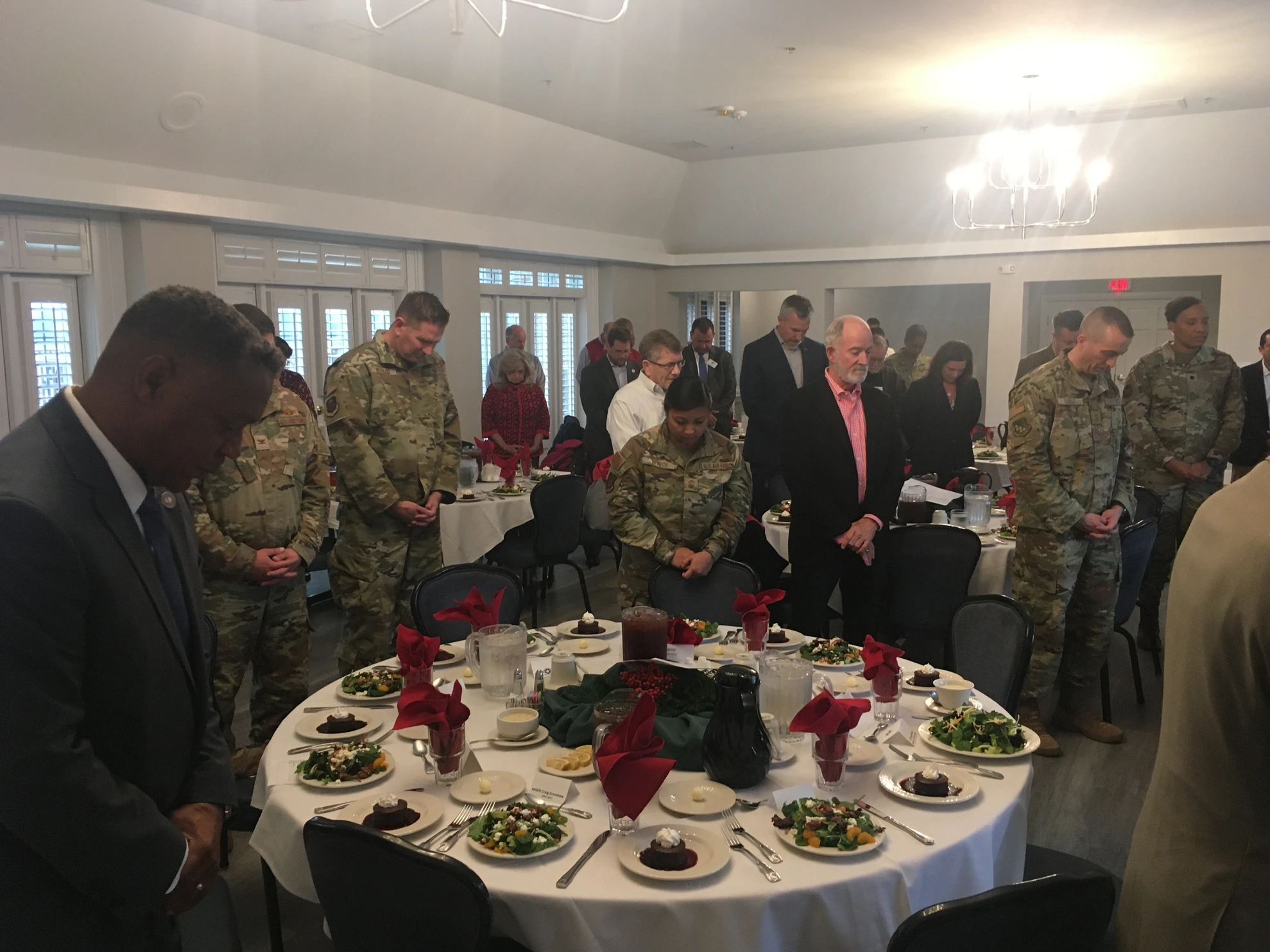 Attendees standing with heads bowed in moment of prayer
