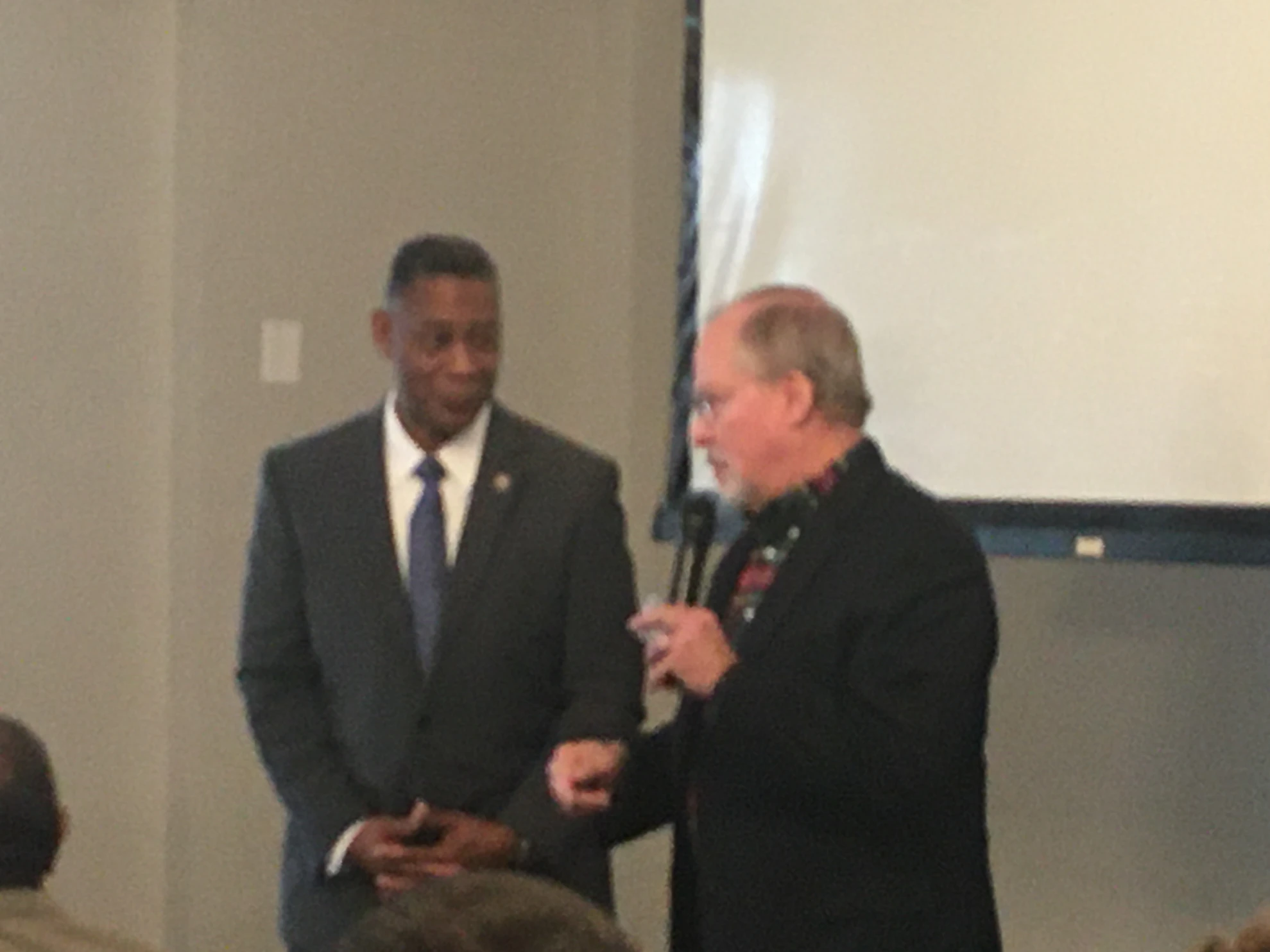 Two men during a presentation - one in suit, one with microphone