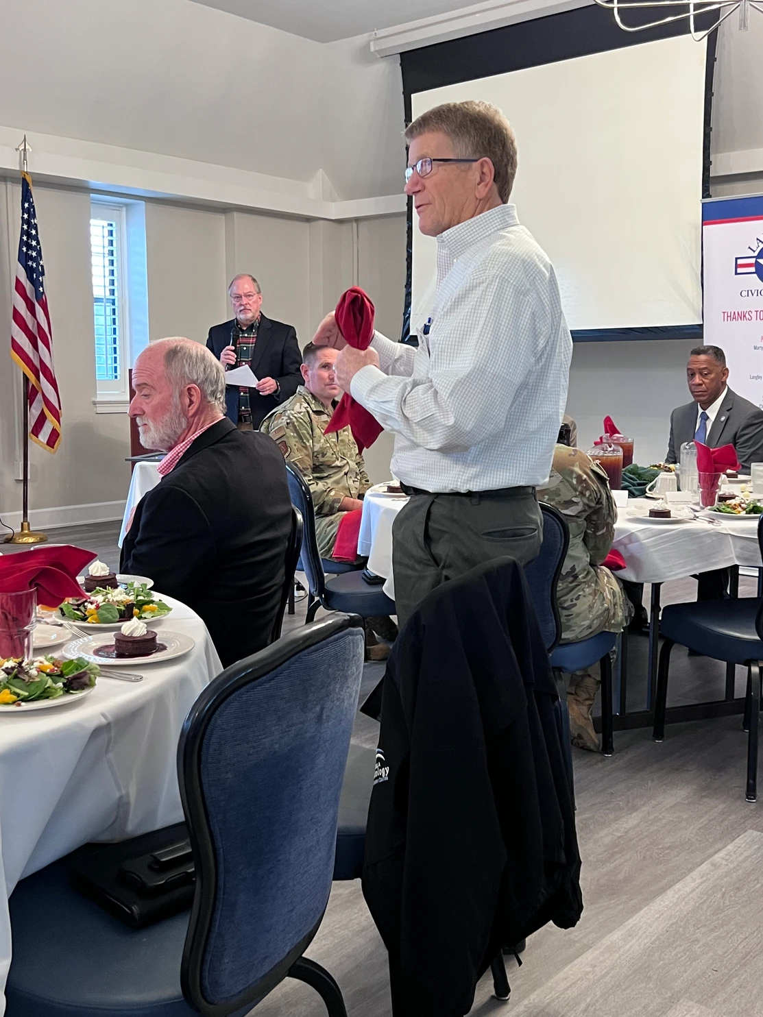 Man standing addressing the room during luncheon