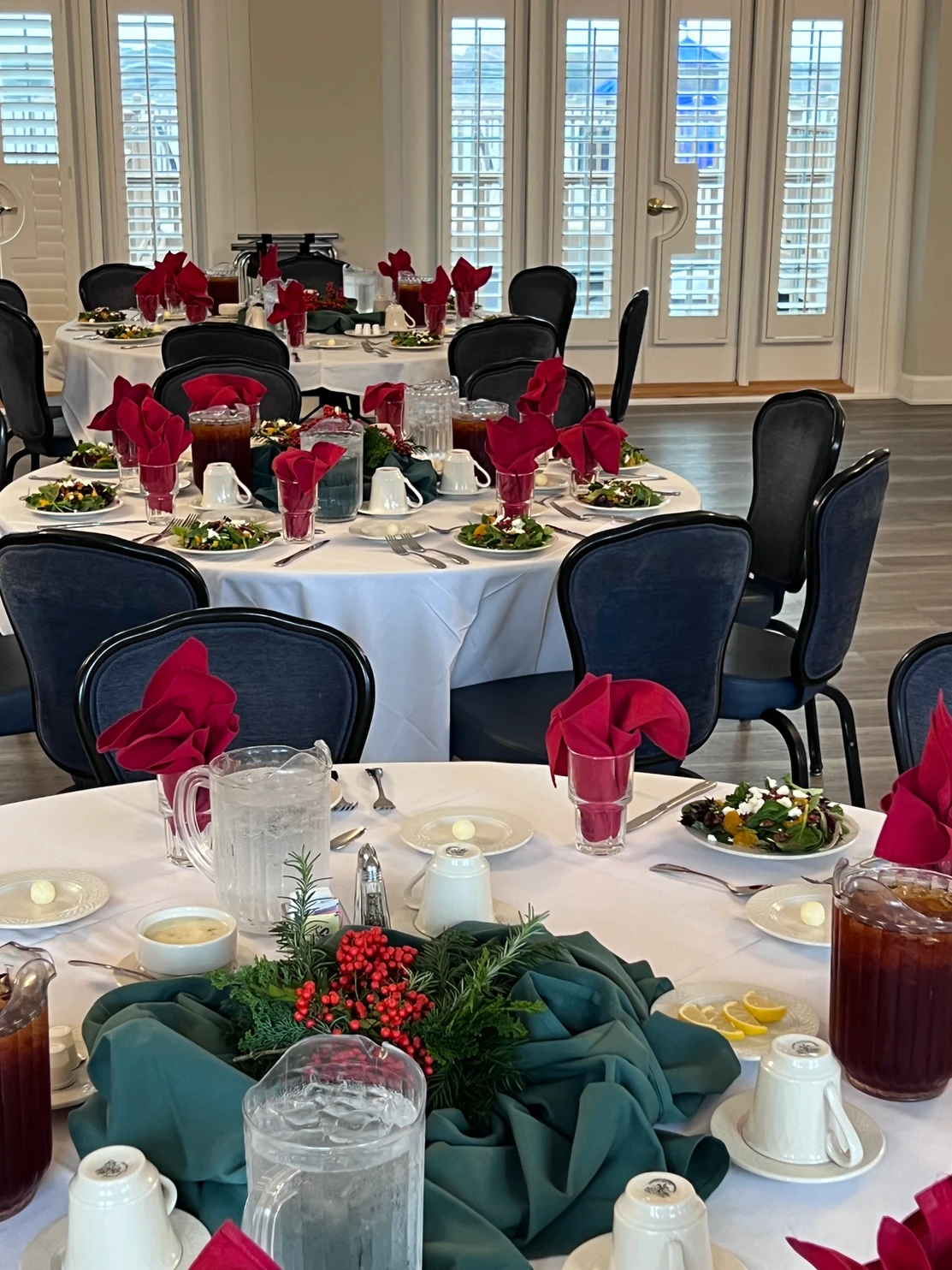 Beautifully set round tables with red napkins and holiday centerpieces