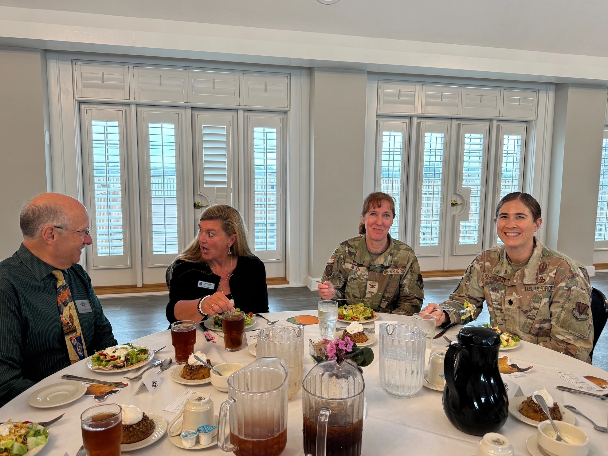 Two civilians and two female military officers at round table