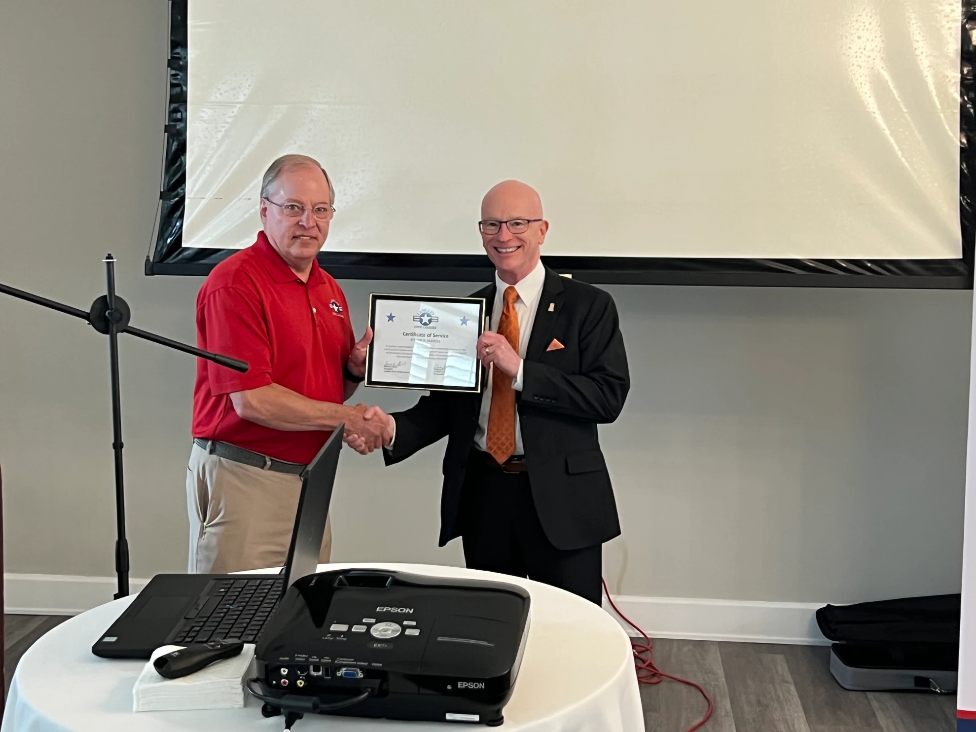 Two men shaking hands while presenting Certificate of Service